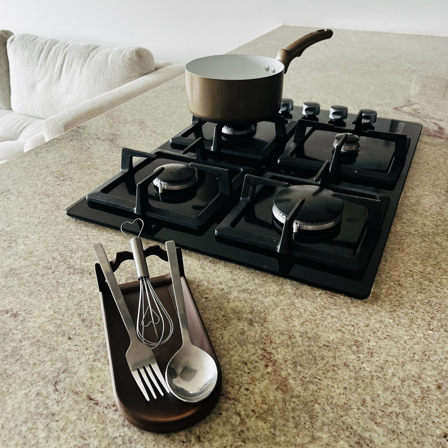 Soporte Dark Chocolate en uso real con cuchara, batidor y tenedor, estufa al fondo