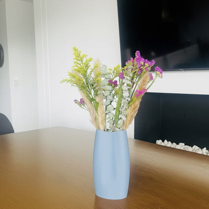 Jarron blue grey con flores sutiles y eucalipto, sala con chimenea y TV, luz natural