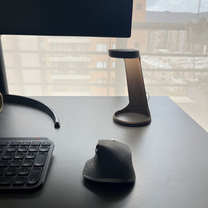 Lampara Chocolate en escritorio con monitor y ventana de fondo, vista alternativa