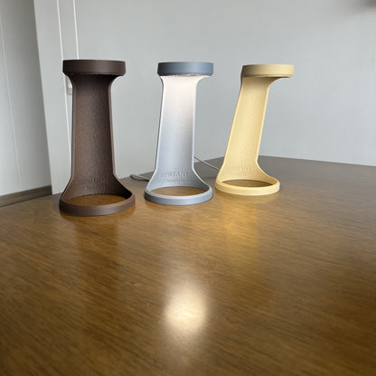 Grupal: variantes Chocolate, Desert Tan y Ash Gray juntas apagadas sobre mesa de madera, fondo pared blanca