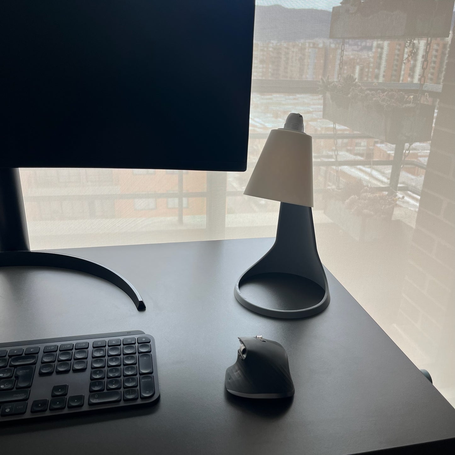 Lampara Curva Ash Gray + Blanco vista 3/4 desde arriba en escritorio con monitor