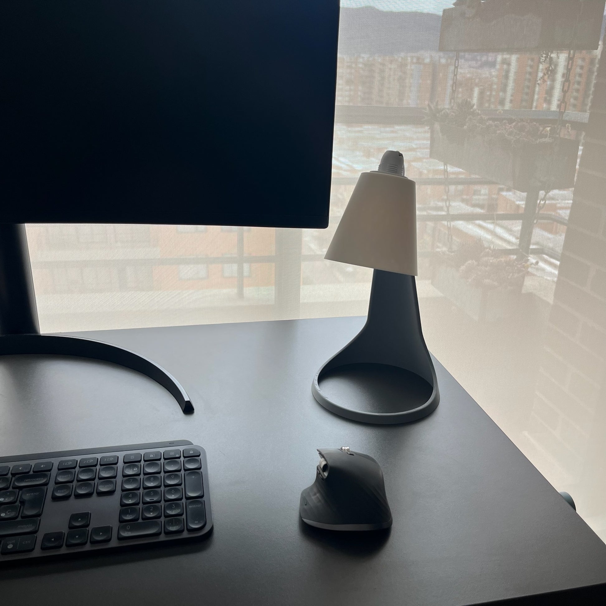 Lampara Curva Ash Gray + Blanco vista 3/4 desde arriba en escritorio con monitor