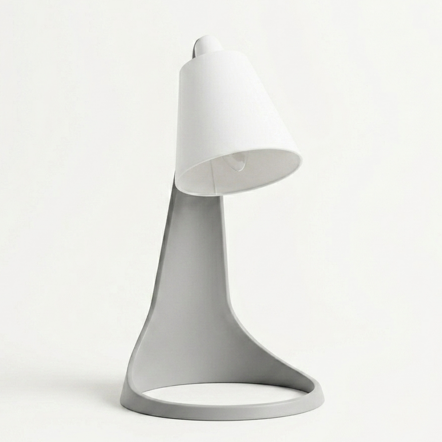 Lampara Curva Ash Gray + Blanco encendida con bombillo visible, en escritorio con monitor y ventana de fondo