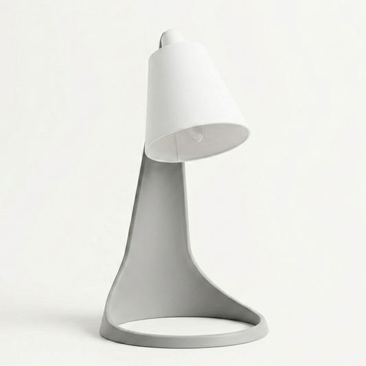Lampara Curva Ash Gray + Blanco encendida con bombillo visible, en escritorio con monitor y ventana de fondo