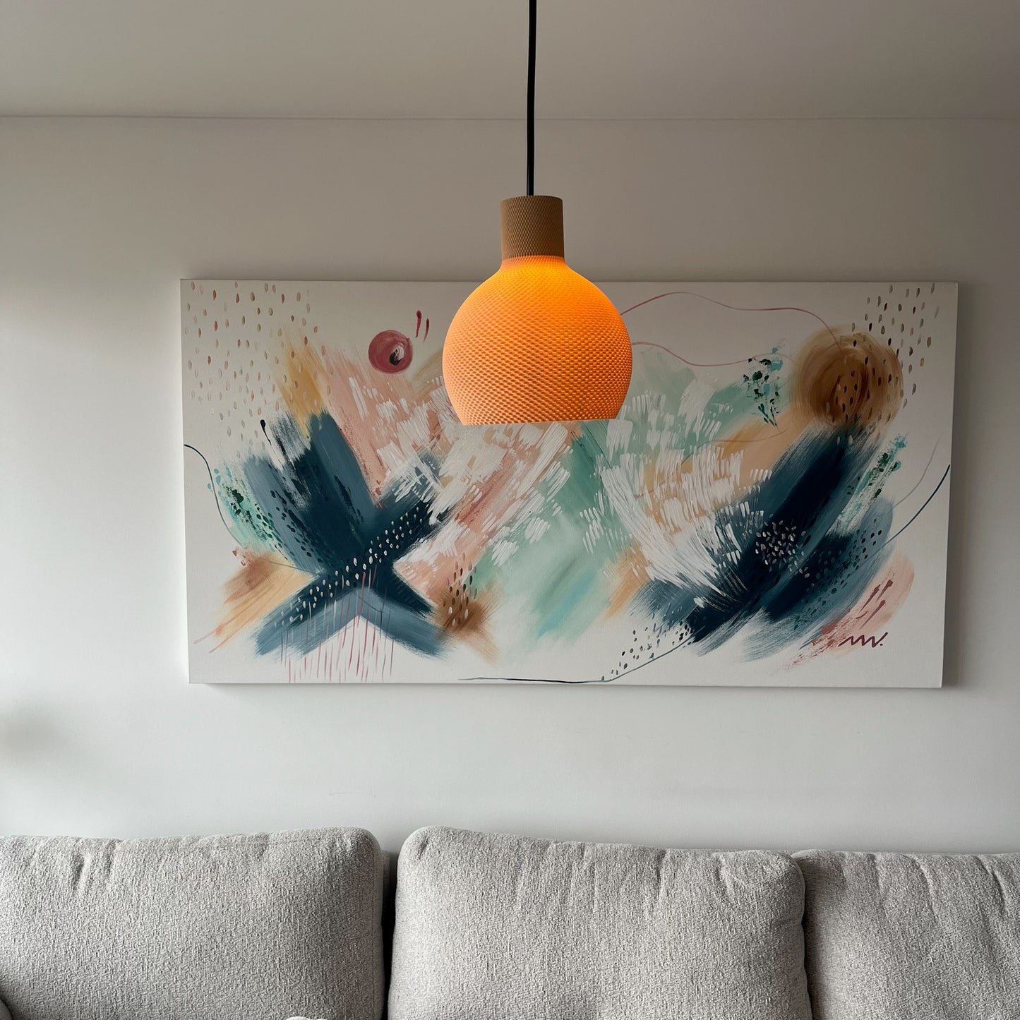 Lampara latte encendida, vertical, colgada sobre el cuadro abstracto en la sala
