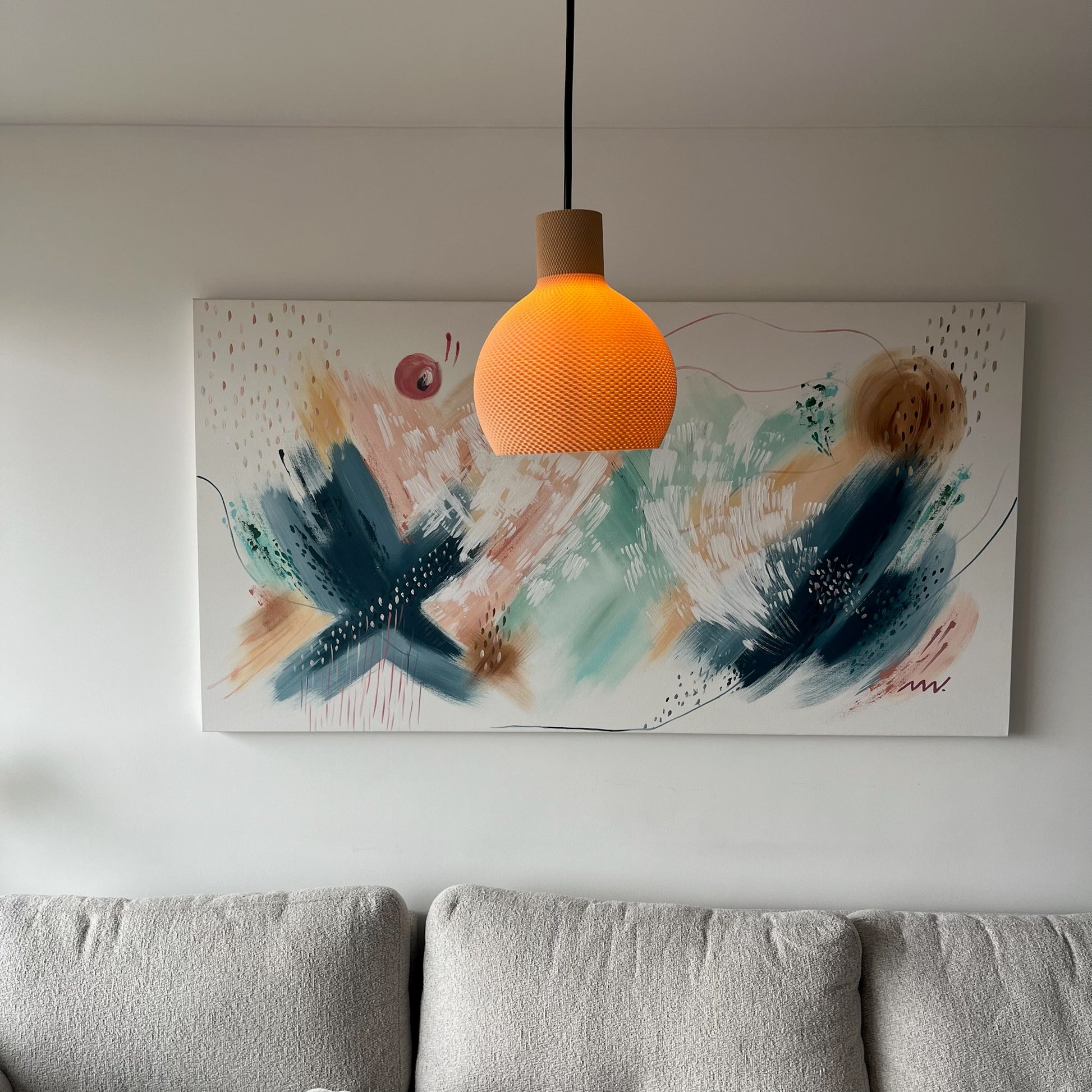 Lampara latte encendida, vertical, colgada sobre el cuadro abstracto en la sala