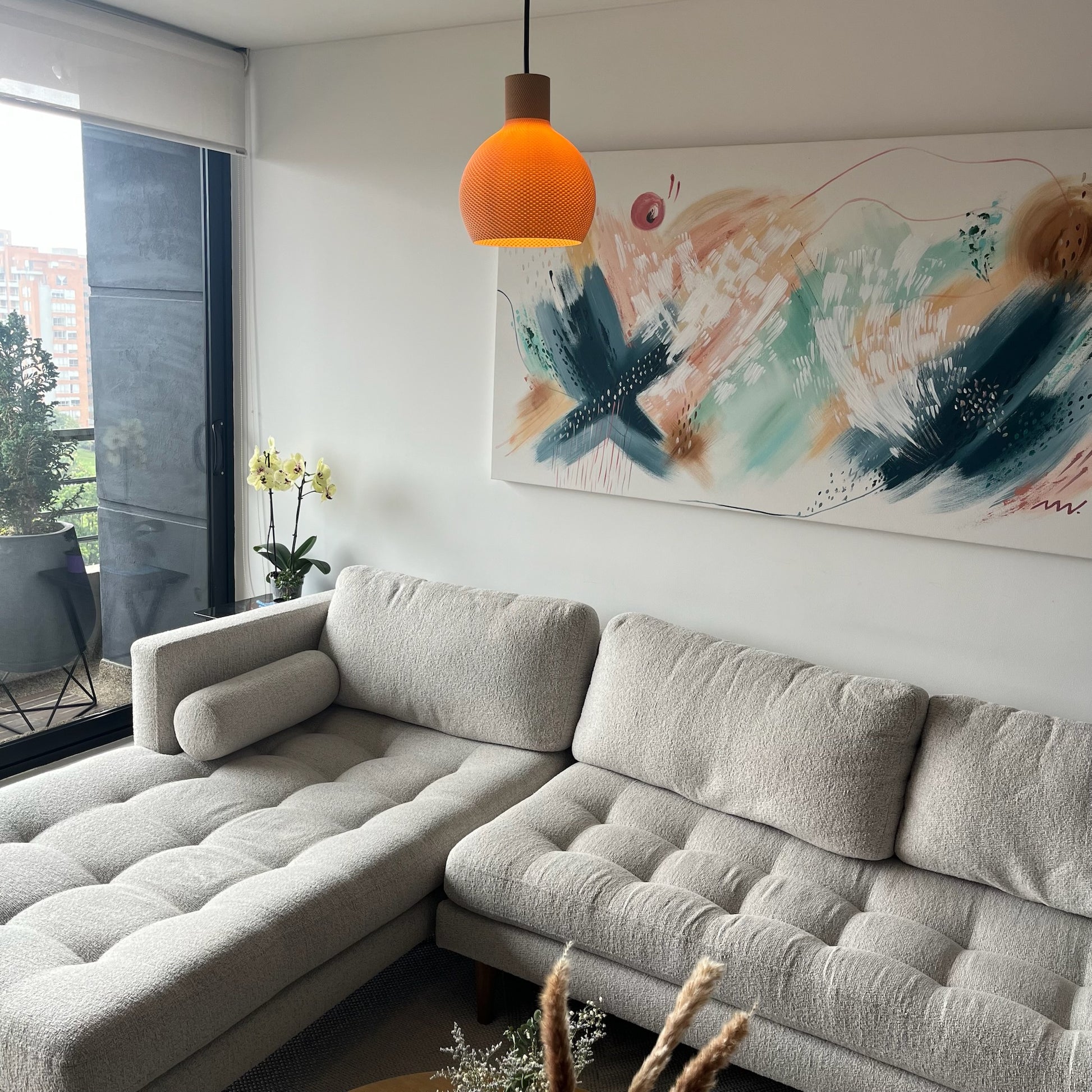 Lampara latte encendida, vista amplia de la sala con sofa, ventanal y plantas