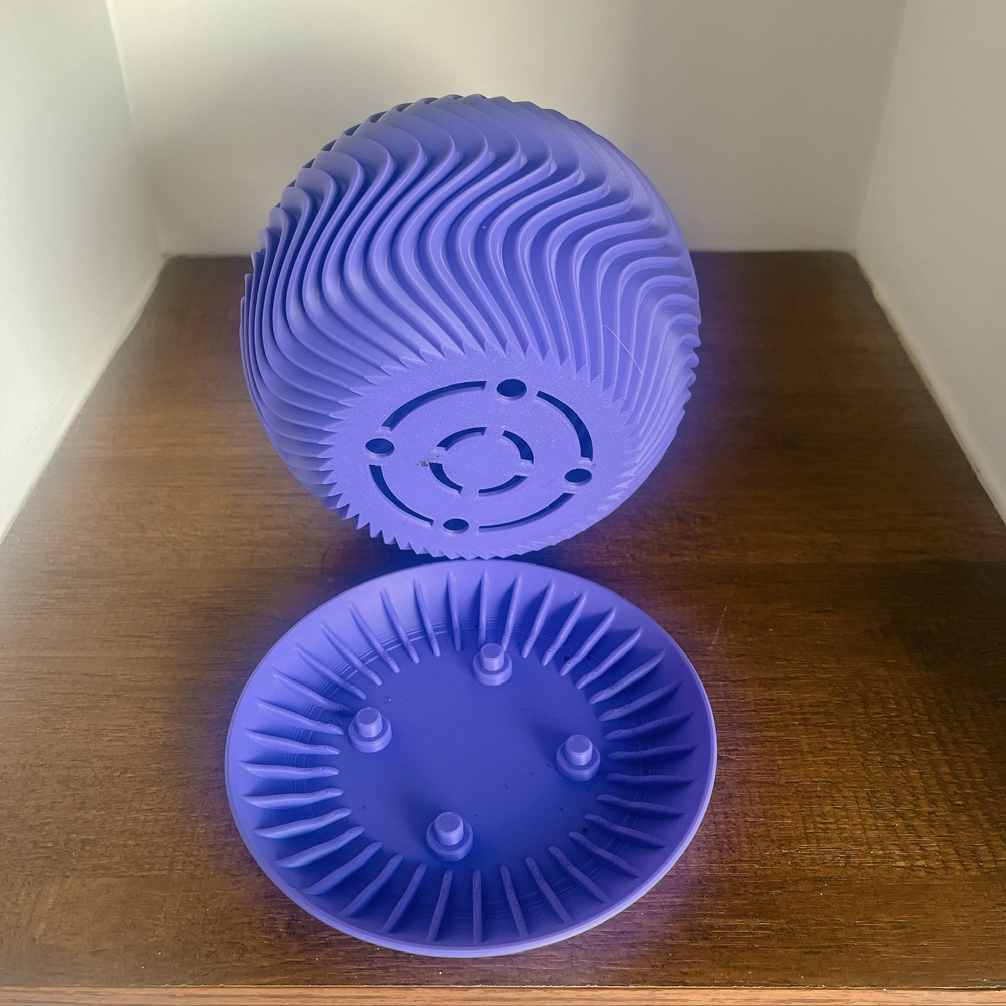 Maceta purple volteada mostrando base con orificios de drenaje circulares, bandeja de drenaje separada al frente con sistema de elevacion