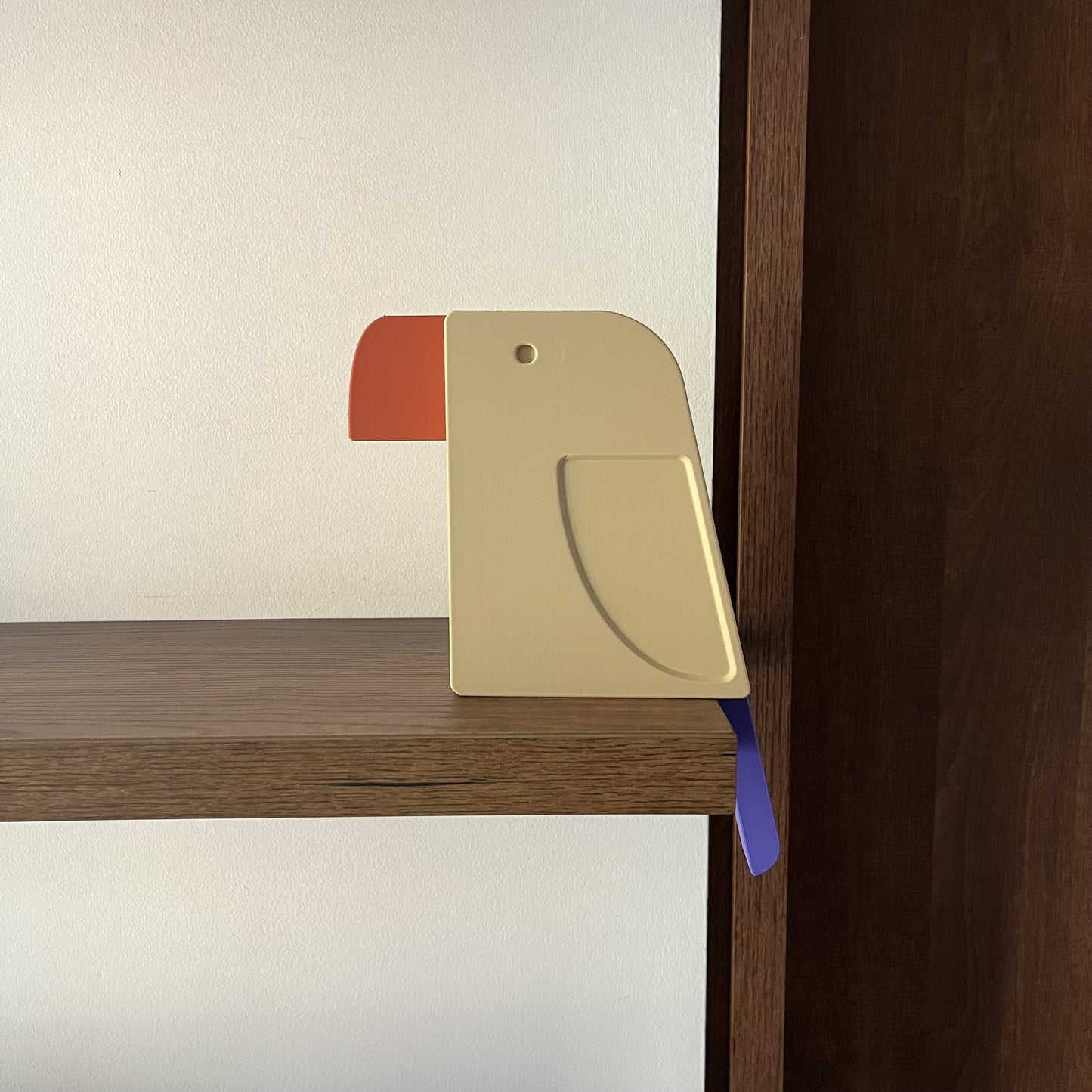 Pieza multicolor — perfil lateral limpio y centrado sobre pared blanca