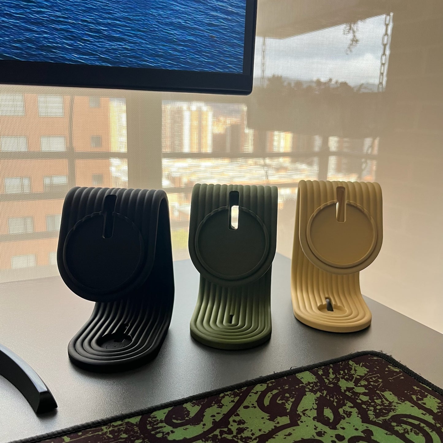 Soporte iPhone + Apple Watch grupal: las 3 variantes (Charcoal, Matte Dark Green, Desert Tan) alineadas en escritorio, vista frontal