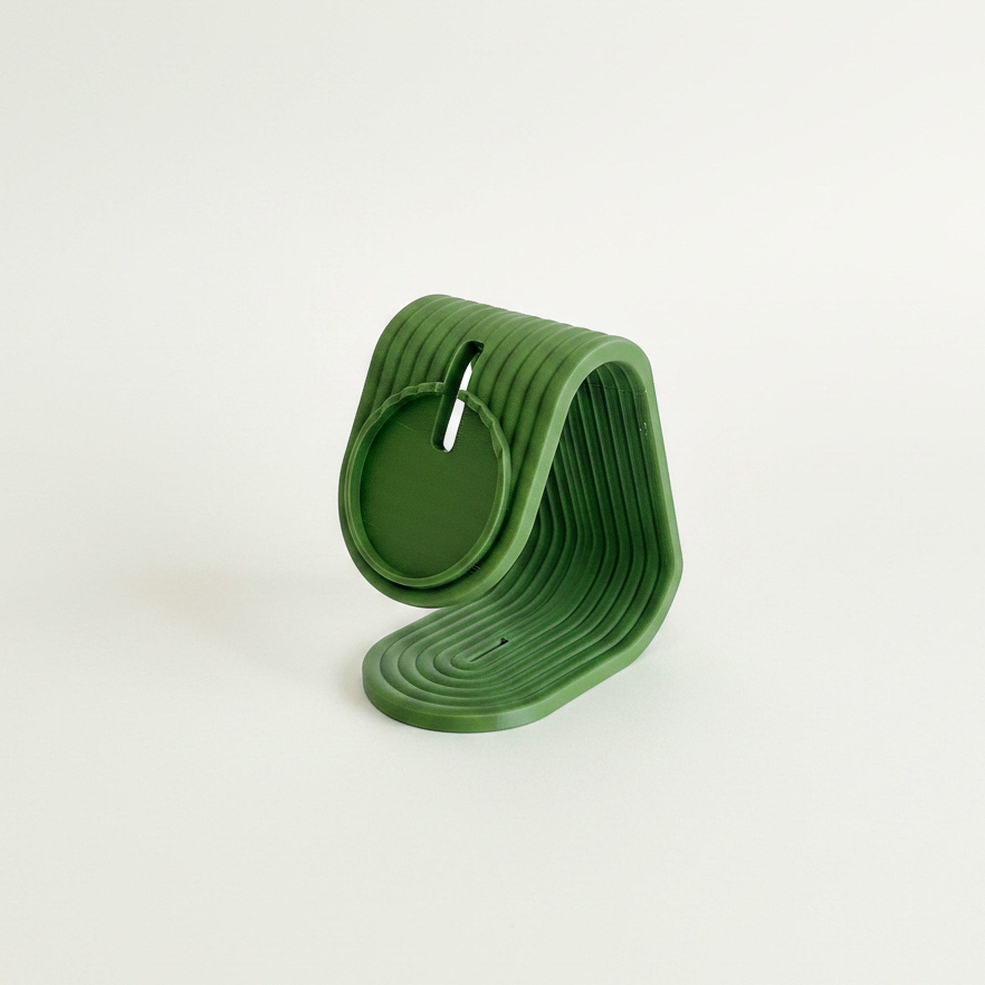 Soporte de carga iPhone Matte Dark Green, vista frontal sobre mesa de madera, mismo encuadre que Charcoal