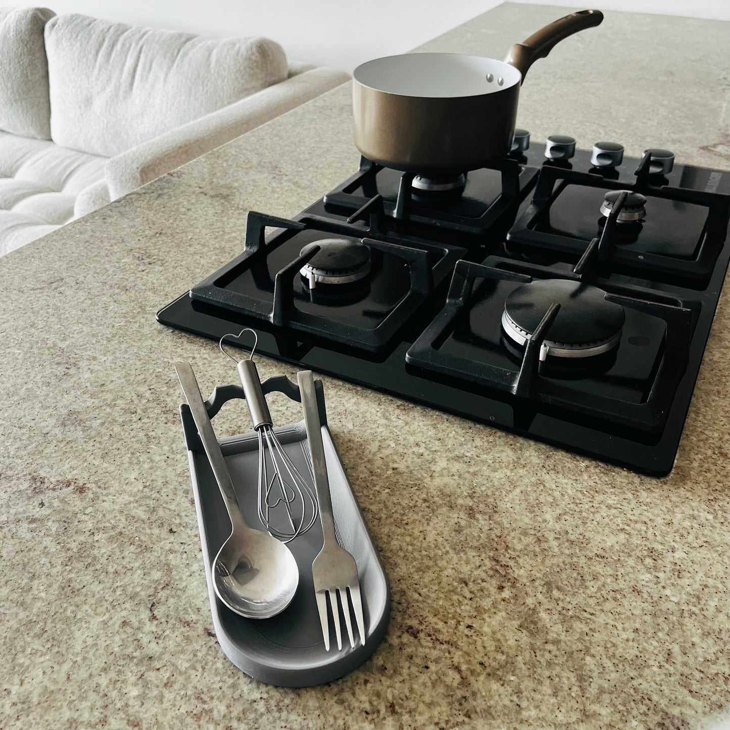 Soporte Nardo Gray en uso real con cuchara, batidor y tenedor, vista superior 3/4, estufa al fondo