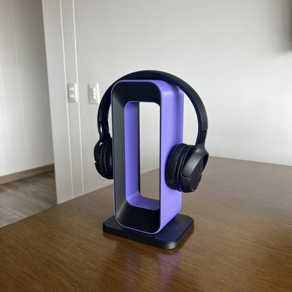 Soporte Charcoal + Purple con audifonos JBL negros puestos, mesa de madera, fondo blanco limpio
